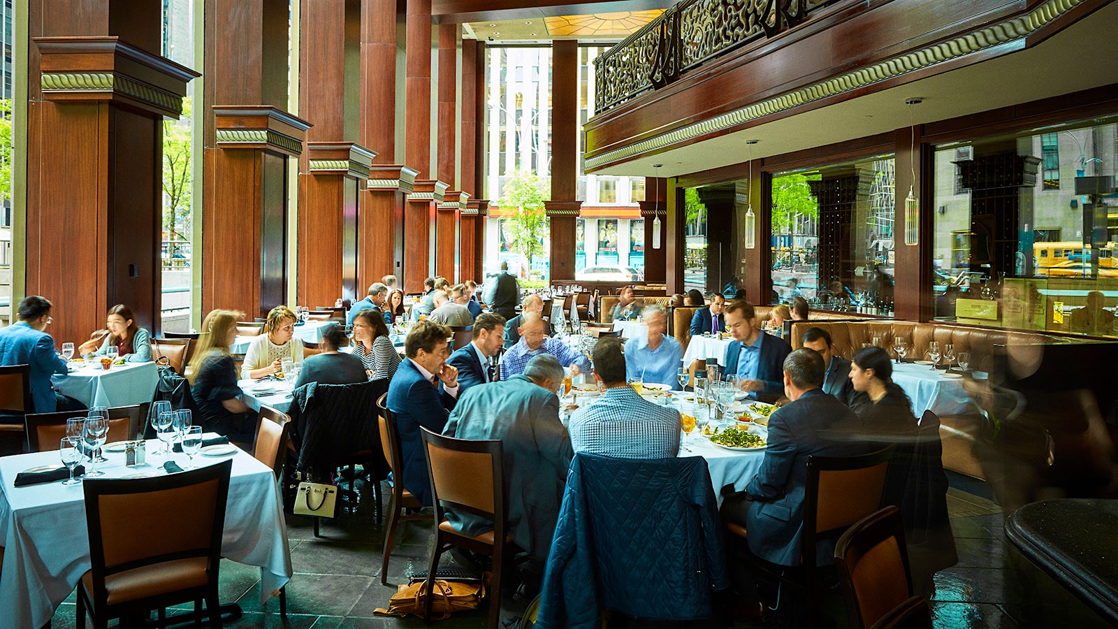 People dining in the dining room at Del Frisco’s Double Eagle Steakhouse with wooden pilasters and a wooden mezzanine overhead